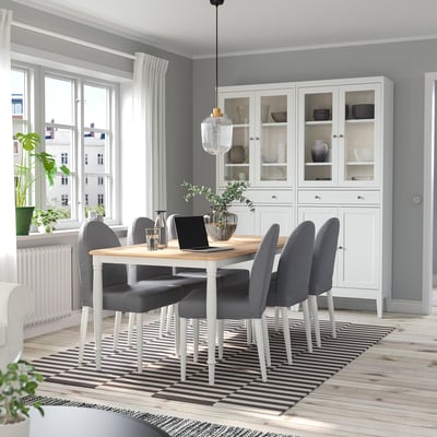Conxunto de comedor moderno con mesa de madeira, cadeiras grises e alfombra a raias.