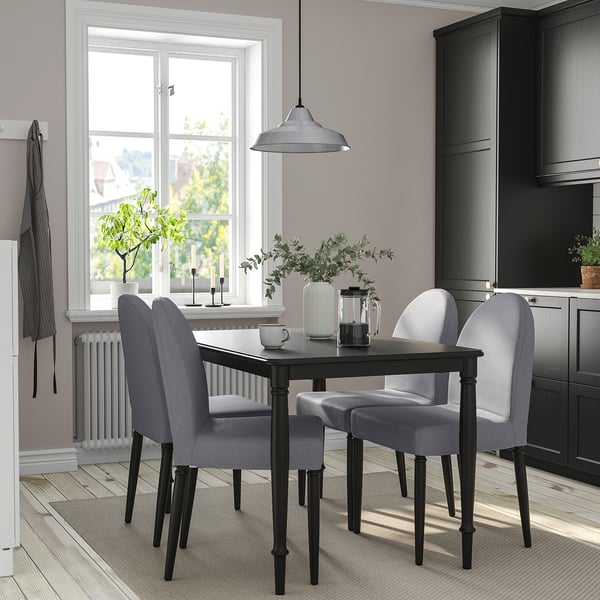 Un elegante conxunto de comedor DANDERYD en gris con cadeiras tapizadas modernas e unha robusta mesa negra, complementando perfectamente a decoración da cociña.