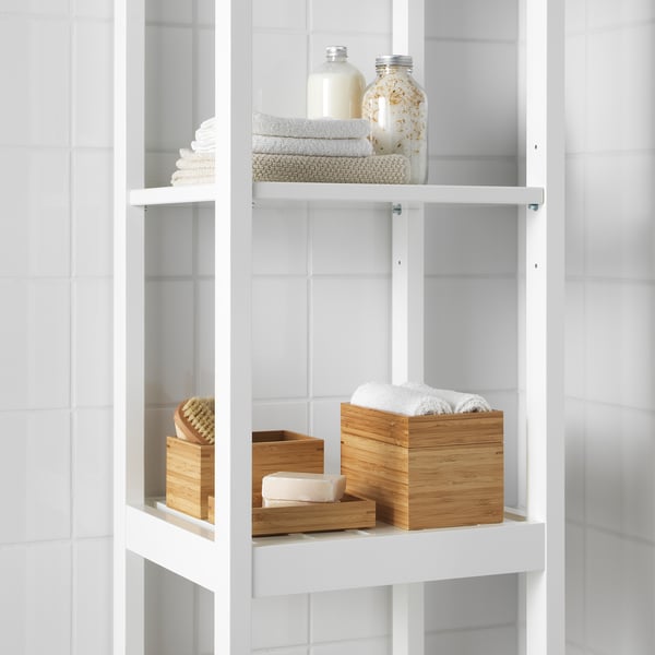 Estantes de baño brancos con toallas e caixas de bambú ben apiladas, unha que contiña algodón.