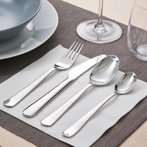Mesa con garfo, coitelo e culleres sobre servilletas grises, prato e vidro.
