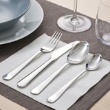 Mesa con garfo, coitelo e culleres sobre servilletas grises, prato e vidro.