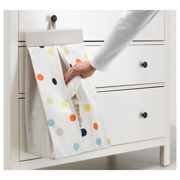 Persoa que abre un soporte de cueiros con puntos de cores unidos a un armario branco.