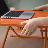 Axustar o soporte portátil laranxa DUBBLA no escritorio, suxeitando o portátil para traballos ergonómicos.