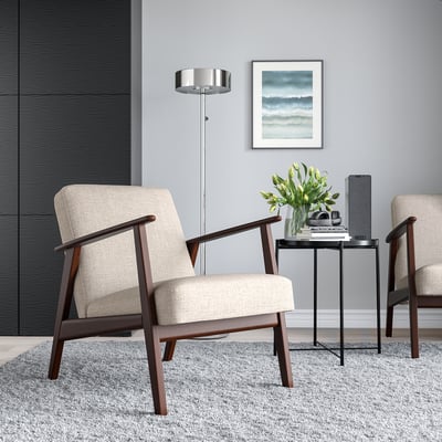 Cadeiras retro, beige, sobre alfombra gris por mesa negra con flores e tableta. Lámpada moderna, arte de temática mariña en ambiente minimalista.