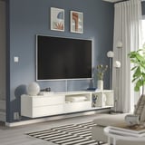 Sala de estar moderna: televisión plana en soporte branco, parede azul, decoración branca, alfombra grande.
