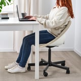 Persoa sentada na cadeira de oficina branca ELDBERGET, escribindo nun portátil no escritorio branco.