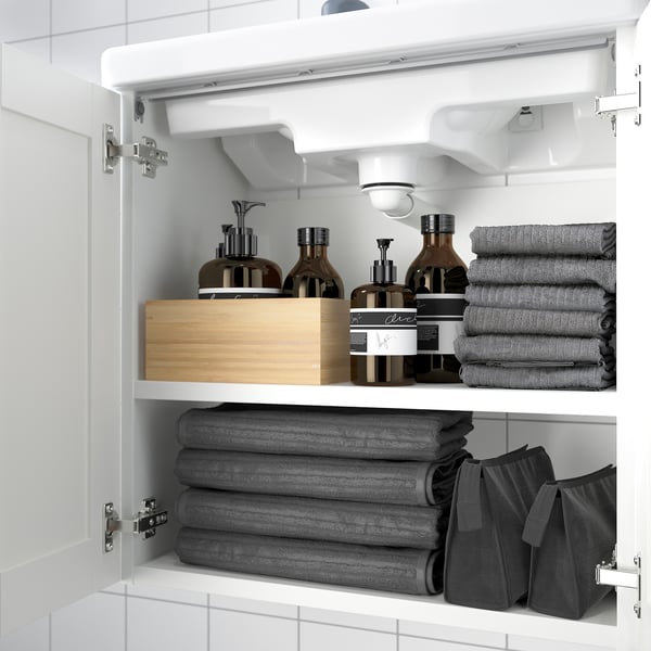 Armario de baño branco con estantes que almacenan toallas e artigos de baño.