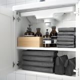 Armario de baño branco con estantes que almacenan toallas e artigos de baño.