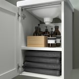Armario de baño aberto con toallas e botellas enroladas, mostrando almacenamento e organización.
