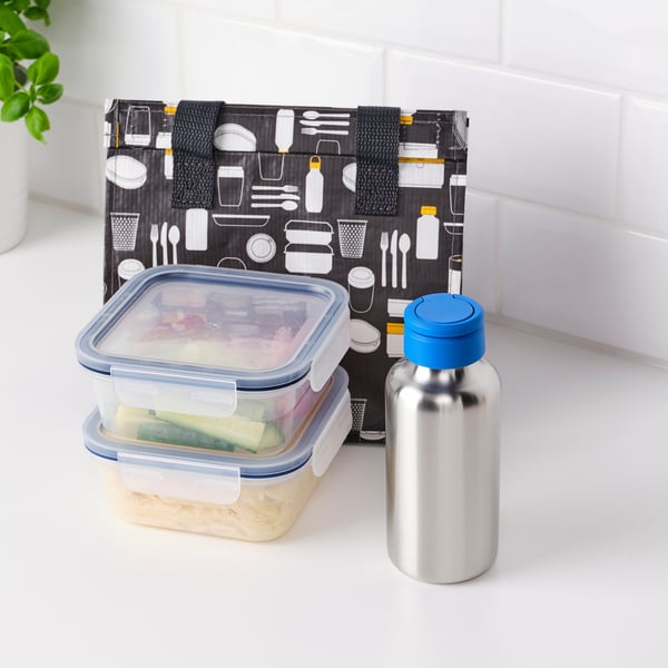 Bolsa de xantar negra con iconas e envases de comida xunto á botella de auga illada no mostrador.