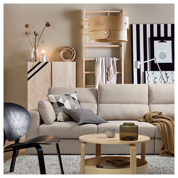 Sala de estar moderna con sofá ESKILSTUNA beige, mesa de café de madeira, cadeira de brazos gris e decoración natural.