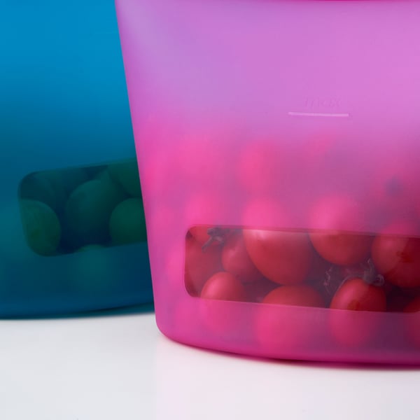 Dúas bolsas de silicona coloridas almacenan alimentos; Un deles ten froitos vermellos.