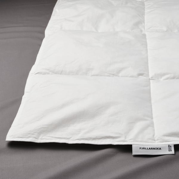 Un duvet branco con patrón de punto de caixa nunha cama. As etiquetas mostran a súa marca fjällräven.