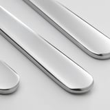 Primeiro plano de coitelos elegantes e pulidos, que reflecten a luz, feitos de aceiro inoxidable brillante.