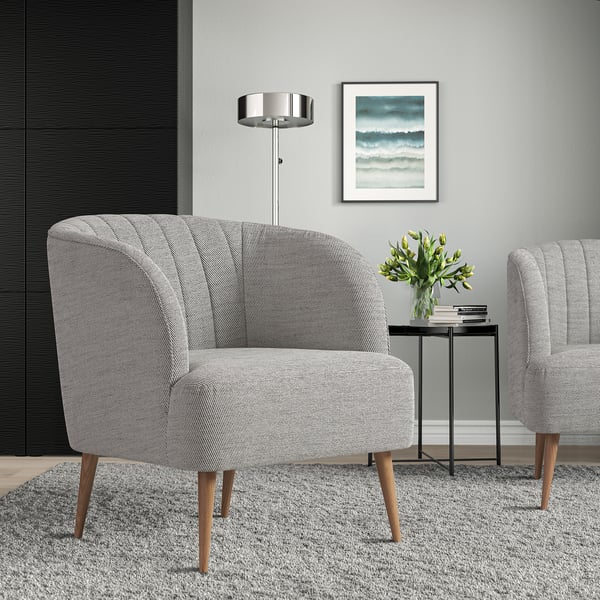 Cadeira de barril gris moderna FULLÖSA, pequena e elegante, patas de madeira; Colocado preto da mesa lateral de metal negro con flores. Obra de arte e lámpada na parede.
