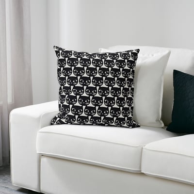 Coxín decorativo de temática de gato en sofá branco.