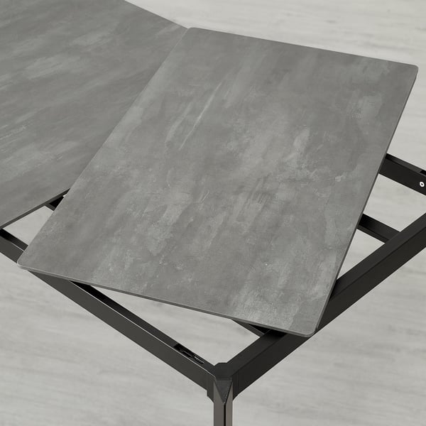 Mesa de comedor extensible con deseño elegante na foto. Superior gris en relevo semellante a pedra, duradeiro e fácil de limpar. As pernas de aluminio proporcionan un soporte robusto.