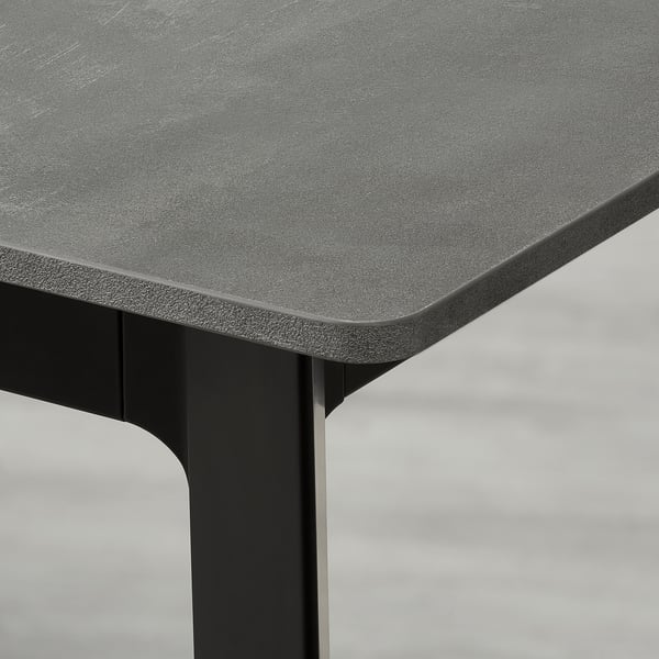 Primeiro plano de mesas de comedor extensibles elegantes, bordo texturizado e robusta perna negra.