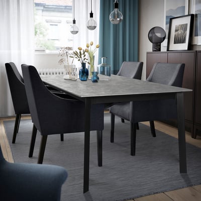 Zona de comedor moderna con mesa extensible, cadeiras, alfombra azul, lámpadas e cortinas.