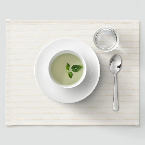 Cunca branca con sopa verde, basilico, culler, cunca sobre alfombra.