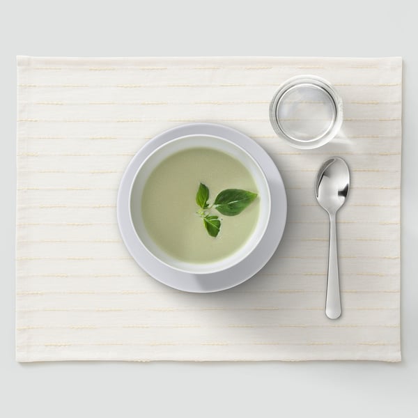 Cunca de sopa verde con culler e vaso pequeno sobre alfombra beige.