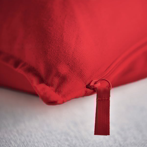 Cuberta de coxín vermella na cama, detalle de cremalleira mostrado, tecido de alta calidade.