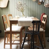 Mesa de comedor de madeira rústica con cadeiras, paredes verdes, coxíns, corredor de tea, flores secas.