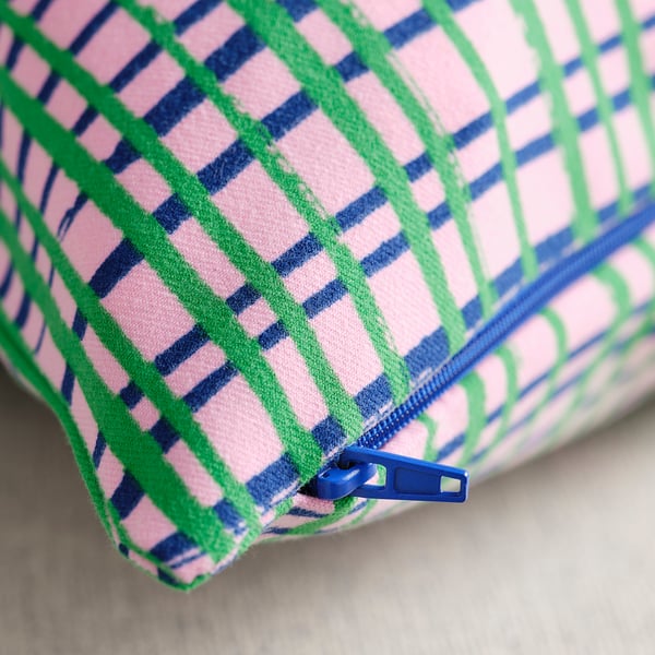 Primeiro plano de cuberta de coxín de cores con cremalleira, patrán rosa, verde e azul vibrante.