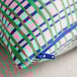 Primeiro plano de cuberta de coxín de cores con cremalleira, patrán rosa, verde e azul vibrante.
