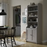 Comedor moderno con armario gris HAUGA, cadeiras negras, luz colgante e armario con roupa.