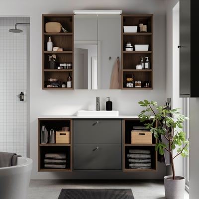 Baño moderno con vaidade gris escuro HAVBÄCK, espello e estantes abertos contra unha parede de baldosas brancas. Inclúe lavabo e almacenamento.