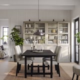 Zona de comedor minimalista con taboleiro HAVSTA, mesa, cadeiras, lámpada, plantas e fundas de vidro.