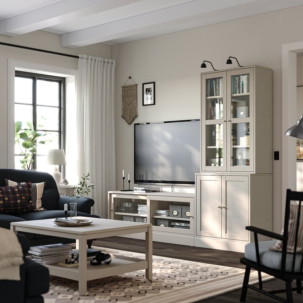 Sala de estar moderna con unidade de televisión de madeira clara, estante e sofá escuro. Televisión de pantalla plana, mesa de café, cortinas e decoracións de paredes.