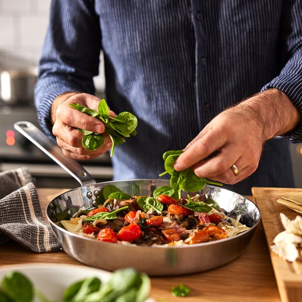 Cociñar espinacas con tomates, cogomelos en tixola de aceiro inoxidable.