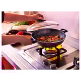 Levanta a man a tapa do wok na estufa, mostrando comida frita con vapor subindo, indicando a cocción activa.