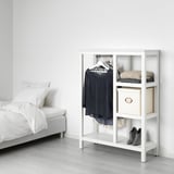 O armario de HEMNES: branco, piñeiro, delgado, xunto á cama, con estantes abertos e varandas para a roupa.