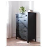 Cofre HEMNES de madeira negra con cinco caixóns, rematado cunha planta e libros.