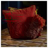 Cesta de arame decorativa con mantas vermellas, ideal para almacenar obxectos grandes preto do sofá ou da cheminea.