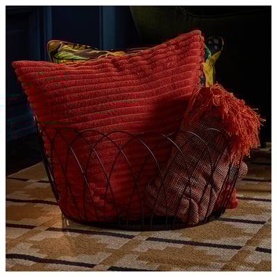 Cesta de arame decorativa con mantas vermellas, ideal para almacenar obxectos grandes preto do sofá ou da cheminea.