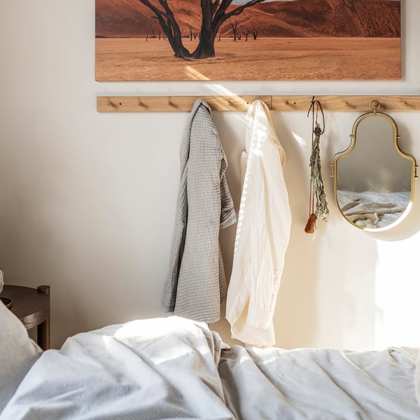 Dormitorio con cama branca, abrigo de carballo, toallas grises e brancas, espello dourado, arte do deserto.