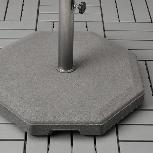Base de parasol de formigón pesado con poste metálico e mangos, deseñado para estabilidade ao aire libre e facilidade de movemento.