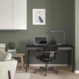 Oficina na casa moderna con escritorio IDÅSEN negro, portátil, cadeira e decoración.