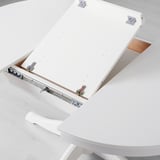 Mesa de comedor branca extensible. A folla da mesa é extraída, revelando o mecanismo de autoalmacenamento que amplía a capacidade de asento.