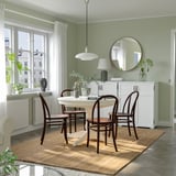 Comedor acolledor con mesa extensible INGATORP e cadeiras de madeira escura nunha alfombra de xute, colocada contra paredes verdes con luz natural.