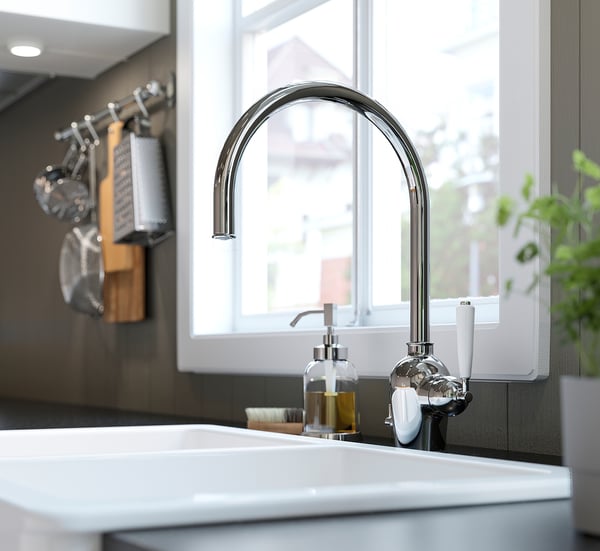 Lavabo de cociña moderno con billa cromado INSJÖN, deseño curvo elegante, soporte de utensilios de madeira e xanela.