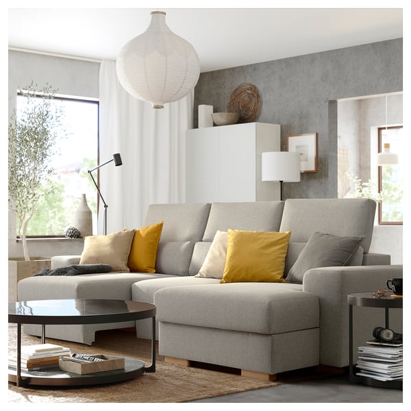 Sofá gris moderno en forma de L con almofadas amarelas, mesa de café elegante, lámpada colgante elegante nun espazo de vida minimalista.