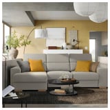 Sala de estar moderna con sofá gris ISTABY, almofadas amarelas, mesa de café, libros, plantas decorativas e parede amarela.