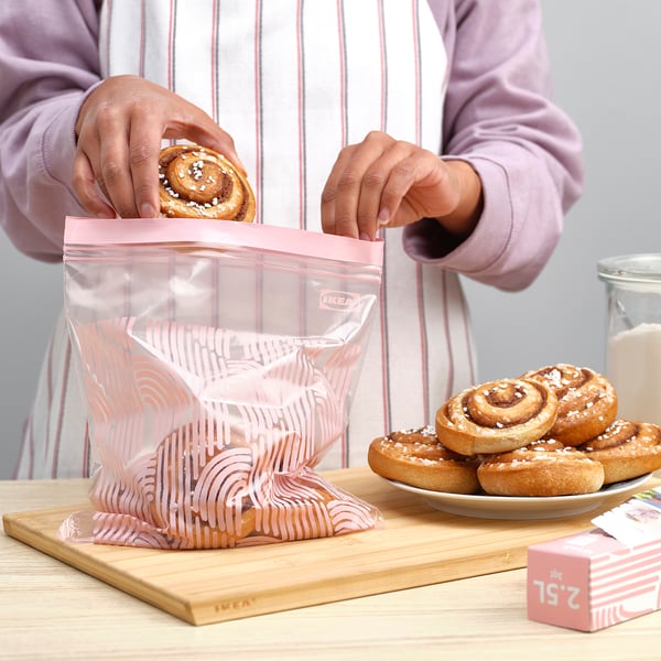 A persoa coloca a pastelería nunha bolsa reutilizable de ikea ISTAD sobre taboleiro de madeira, mostrando a súa fresca conservación e organización.