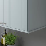 Armario de cociña moderno con acabado gris-azul brillante, luces e cordóns ocultos, cunha planta e botellas ao seu lado.