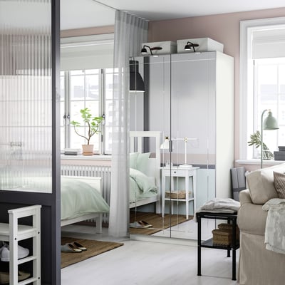 Dormitorio moderno con armario KAMMARTORP, cama, mesa de noite e sofá.